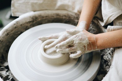 ceramic working process with clay potter's wheel. young woman making pottery in studio. female hands on pottery wheel