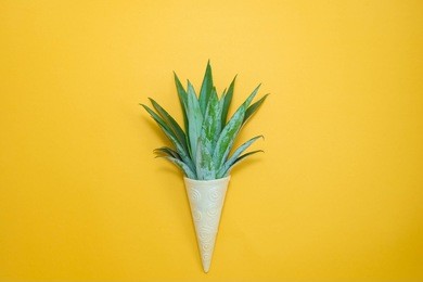 ice cream cone with pineapple leaves on orange background. fruit and candy concept. flat lay.