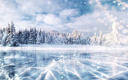 cracks on the surface of the blue ice. frozen lake in winter mountains. it is snowing. the hills of pines. carpathian ukraine europe
