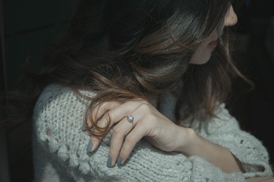close up beauty section portrait view of a young asian woman natural smile sitting under the sun with an elegant engagement diamond ring on her finger. love and wedding concept.