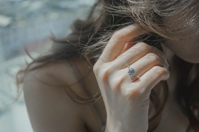 close up of an elegant engagement diamond ring on woman finger. love and wedding concept.
