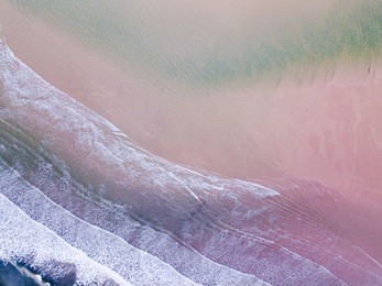 aerial view looking down on a welsh beach in the uk. taken 400 feet in the air, looking directly down on deep blue waves and beach