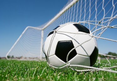 football in the goal net against blue sky