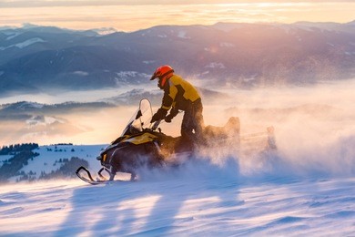 a man is riding snowmobile in mountains. beautiful morning light. blue shadows.