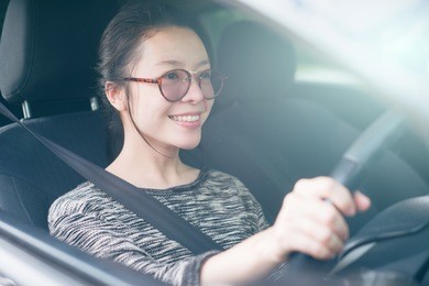 attractive cute young asian woman in casual wear looking forward while driving a car. smile and happy time to travel or rest concept. filtered image. soft light effect added. fasten seat belt.