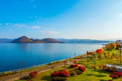 park near lake toya in toyako town, hokkaido, japan.  lake toya in beautiful morning with cloudy blue sky and mountain background. 