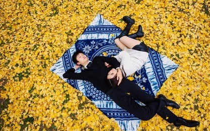 high angle view of couple of chinese young people lying on autumn ground covered with golden ginkgo leaves, full of love, lover concept.