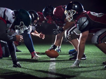 american football players are ready to start on field at night