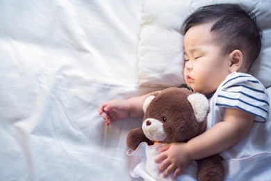 newborn baby sleep with teddy bear on ther bed