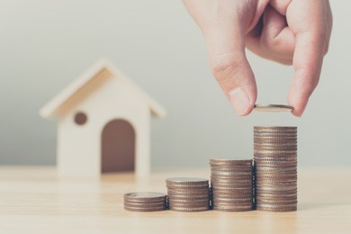 property investment and house mortgage financial concept, hand putting money coin stack with wooden house