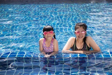 asian happy family in swimming pool at water park