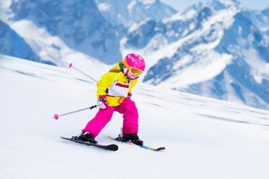 child skiing in mountains. active toddler kid with safety helmet, goggles and poles. ski race for young children. winter sport for family. kids ski lesson in alpine school. little skier racing in snow