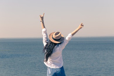 young asian woman raise her hands up by the sea, vacation time, happy holiday.