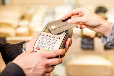 woman paying with card contactless in the food store. close-up view on the terminale and card