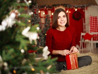 woman with presents on background of christmas tree and new year decorations 