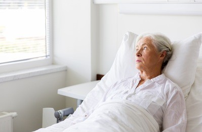 medicine, healthcare and old people concept - sad senior woman lying on bed at hospital ward