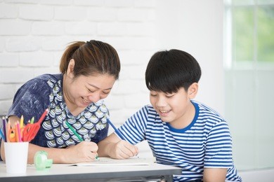 asian boy with mother teaching and learning your homework at home 
