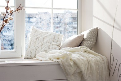 cushions and a knitted plaid on the windowsill. a cozy winter window sill. 
