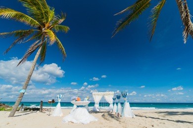 wedding arch decorated with white and blue flowers on the coastline of caribbean sea in summer sunny day