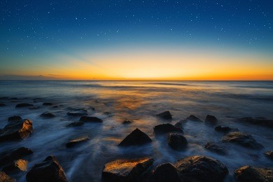 beautiful sunset scenery of the sea with blue sky and stunning ray of light. glowing star effect.