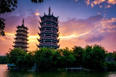 beautiful sunrise with colorful sky at guilin's sun and moon twin pagodas (one of the guilin's attractions) in shanhu (shan lake), guangxi, guilin china.