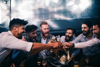 group of young men toasting with beer at a nightclub