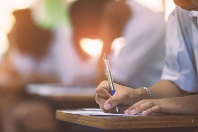 closeup to hand of student  holding pen and taking exam in classroom with stress for education test .