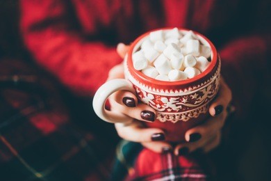 closeup hand of pretty girl with cup of coffee with marshmallow. 