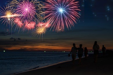 silhouette people looking beautiful fireworks display on the beach ,celebration new year night concept