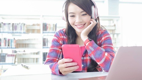 woman student listen music and use cell phone in the library