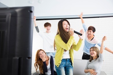 young woman holding microphone and singing at karaoke
