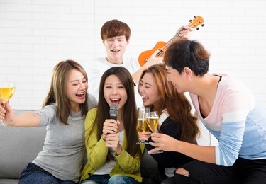 young woman holding microphone and singing at karaoke
