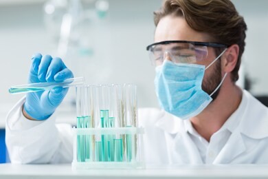 organic chemistry. selective focus of test tubes standing on the shells while being looked at by nice smart male chemist