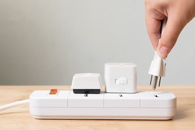 hand of male or female unplugged plug into socket to save energy, reduce energy efficiency concept