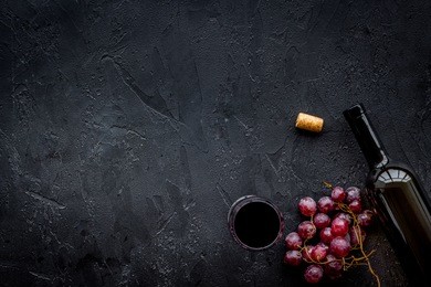 drink wine concept. bottle, glass, grape on black background top view copyspace