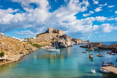 fishing boats and sail boats in st. paulÂ´s bay, lindos acropolis in background (rhodes, greece)