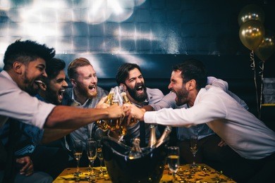 group of young men toasting with beer at a nightclub