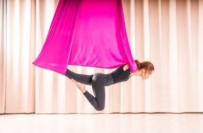 asian woman training in a fitness room with fly yoga elements