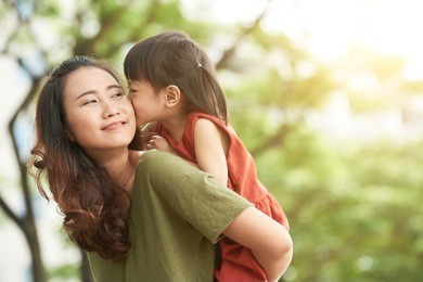 girl kissing mother when she giving her piggyback ride