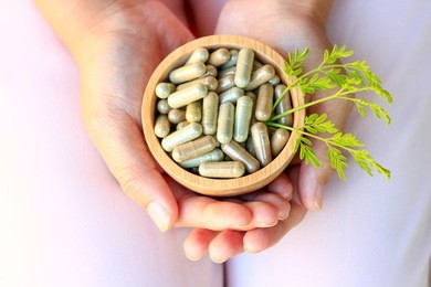 girl hands holding herbal capsules in wooden bowl