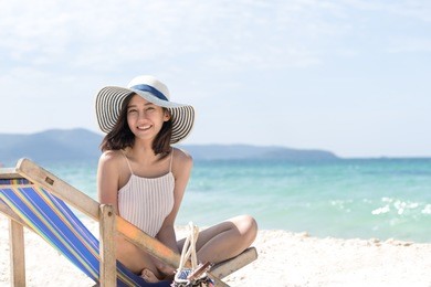 happy asian woman sitting at the beach have copy space on right handside. relax and travel concept.