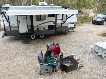 a young attractive couple relaxing at their camp site while rv camping