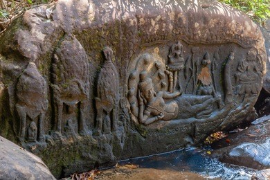 lord vishnu in a reclining repose lying on the serpent god ananta, with goddess lakshmi at his feet and lord brahma on a lotus petal, in kbal spean river bank
