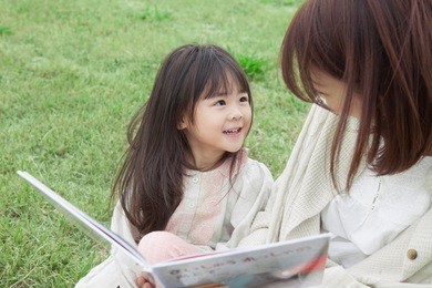 japanese mother and child reading a book on the lawn