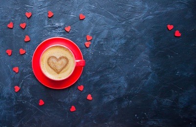 cup of coffee with heart shape on dark blue background for valentine's day greeting card. top view. 