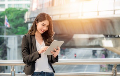 portrait of asian pretty businesswoman in smart casual using digital tablet outdoors