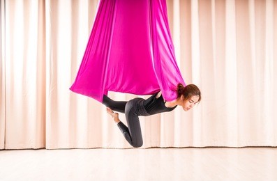 asian woman training in a fitness room with fly yoga elements