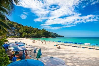 unidentified people are relaxing on kata beach during a sunny day in phuket, thailand. 
