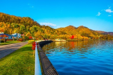 walking path and sitting bench near toya lake. lake toya in toyako town, hokkaido, japan.  lake toya in beautiful morning with clear blue sky and mountain background. 
