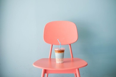 pastel and minimal concept : a clear plastic cup of ice coffee latte with pastel blue straw on pastel pink table on pastel blue background, close up, copy space